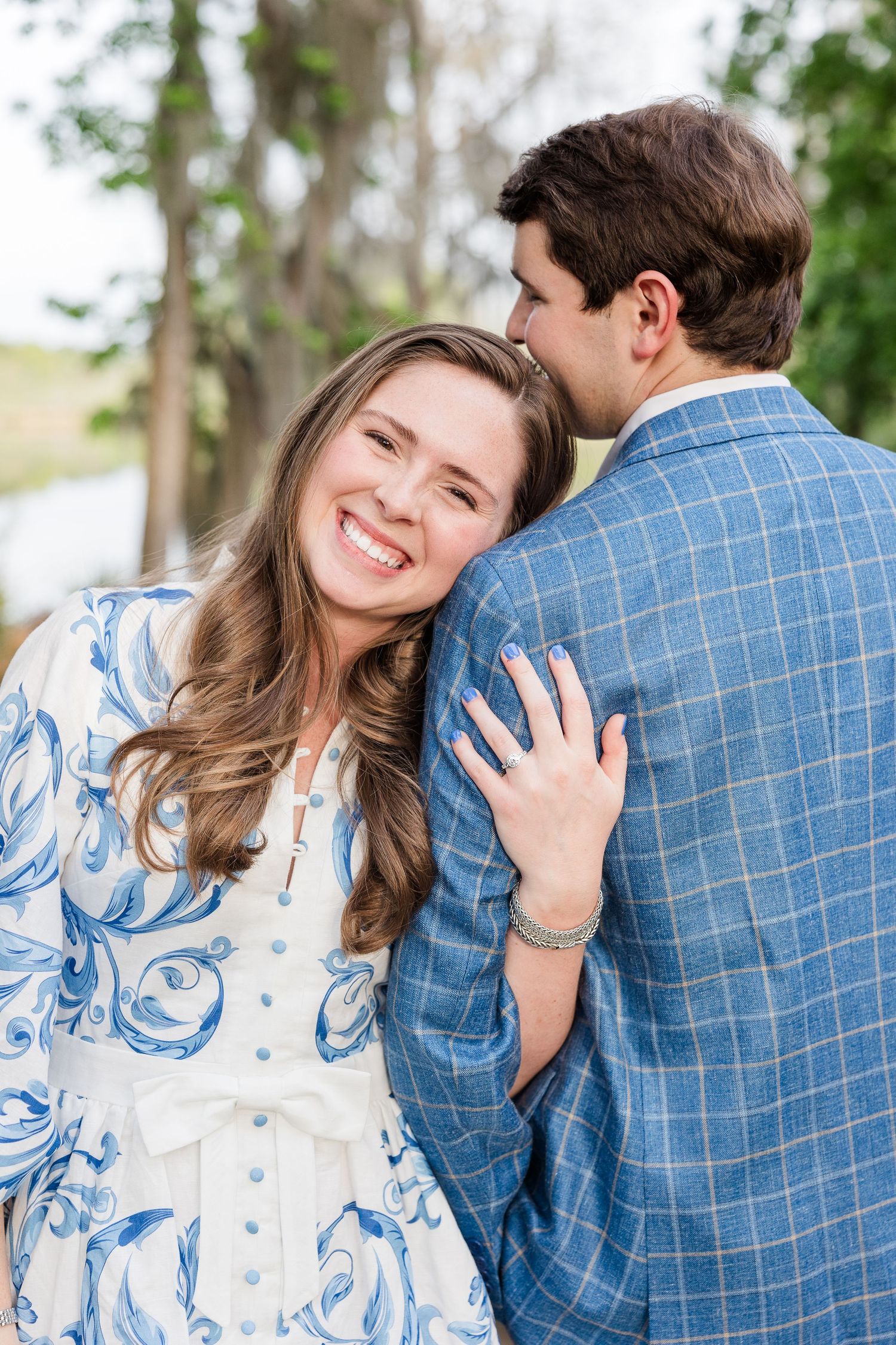 Romantic couple portraits in blue and white outfits under Spanish moss trees.