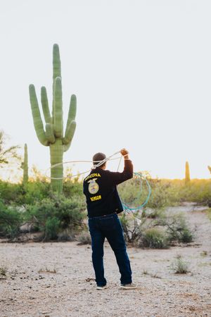 Person wearing FFA jacket performs dance moves in desert setting with saguaro cacti.