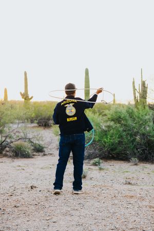 Figure in FFA uniform dances with arms outstretched among desert cacti at dusk.