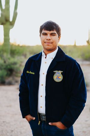 Student wearing FFA jacket and white shirt poses in desert setting.