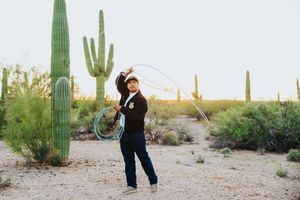 FFA member in navy jacket poses in front of tall saguaro cacti in a desert landscape at sunset.