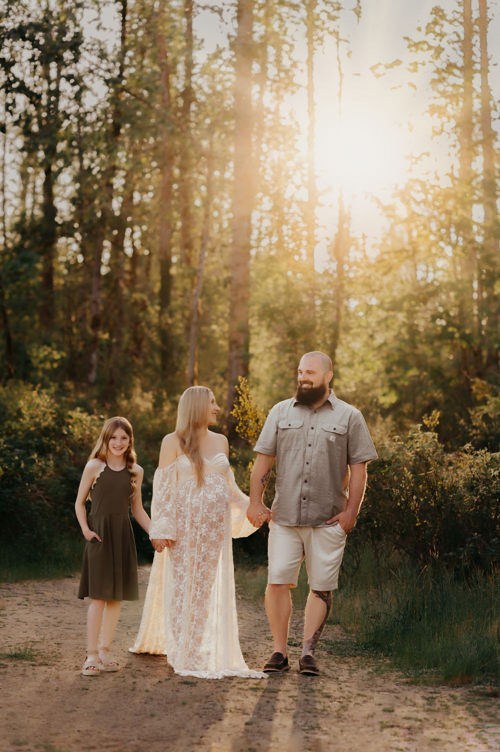 Family portrait in forest setting with sunlight streaming through trees.