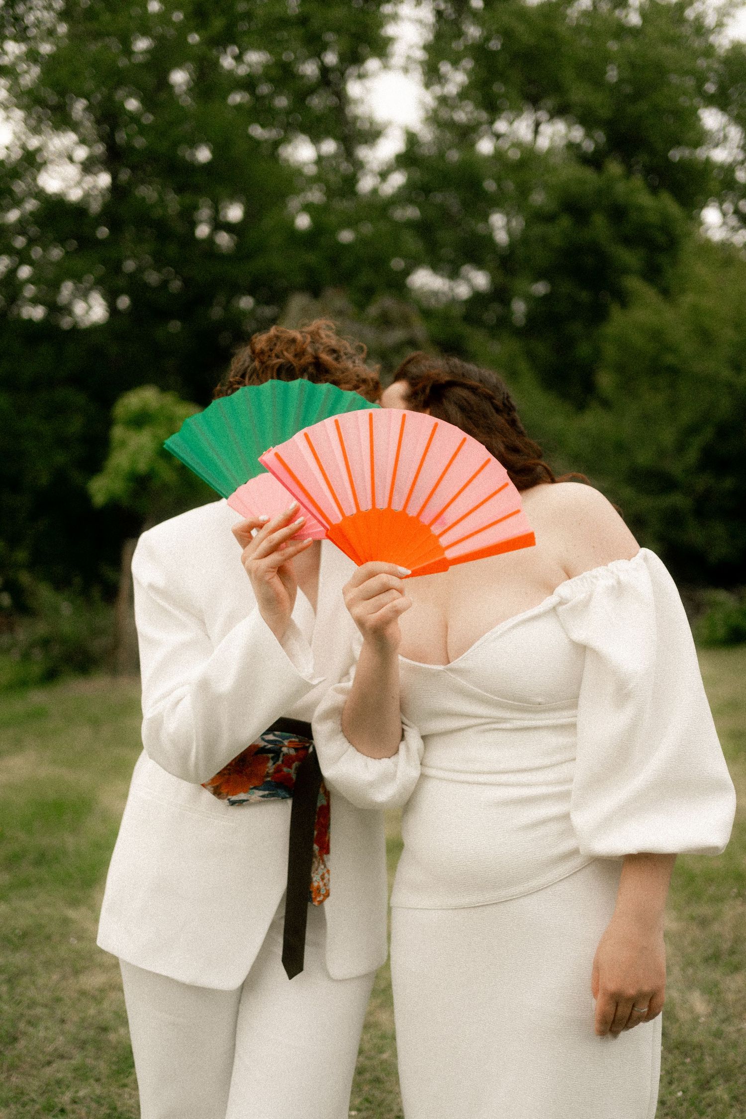 Newlyweds stand in silhouette against a golden sunset in an open field.