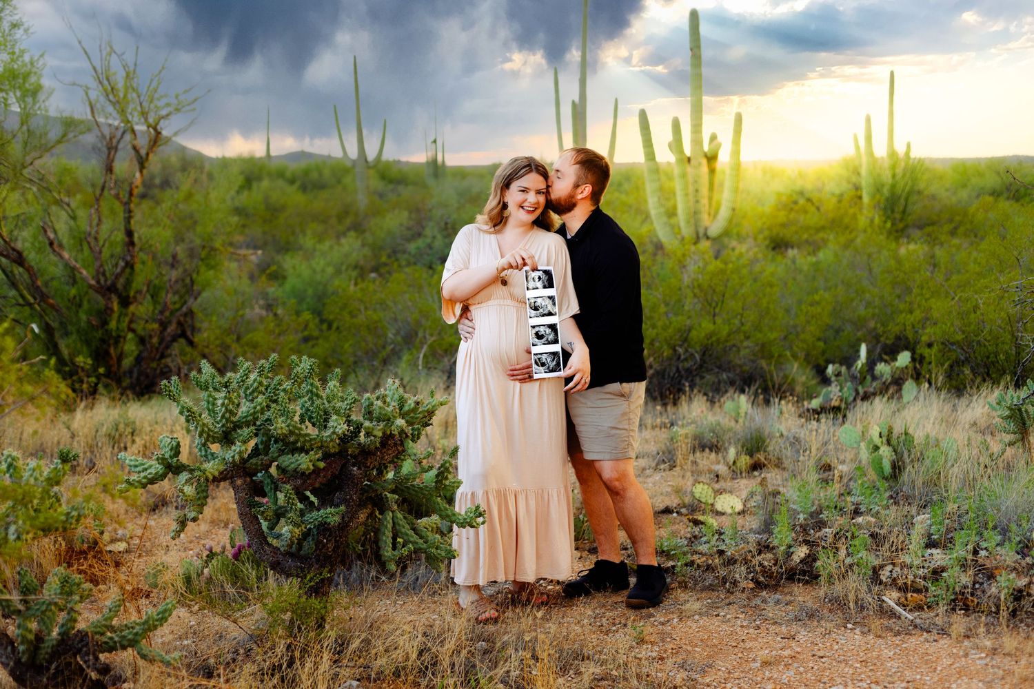 Desert maternity photo session at sunset surrounded by saguaro cacti and desert flora.