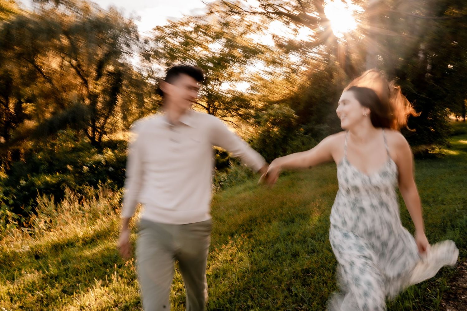 Couple dancing and twirling in a sunlit meadow during golden hour.