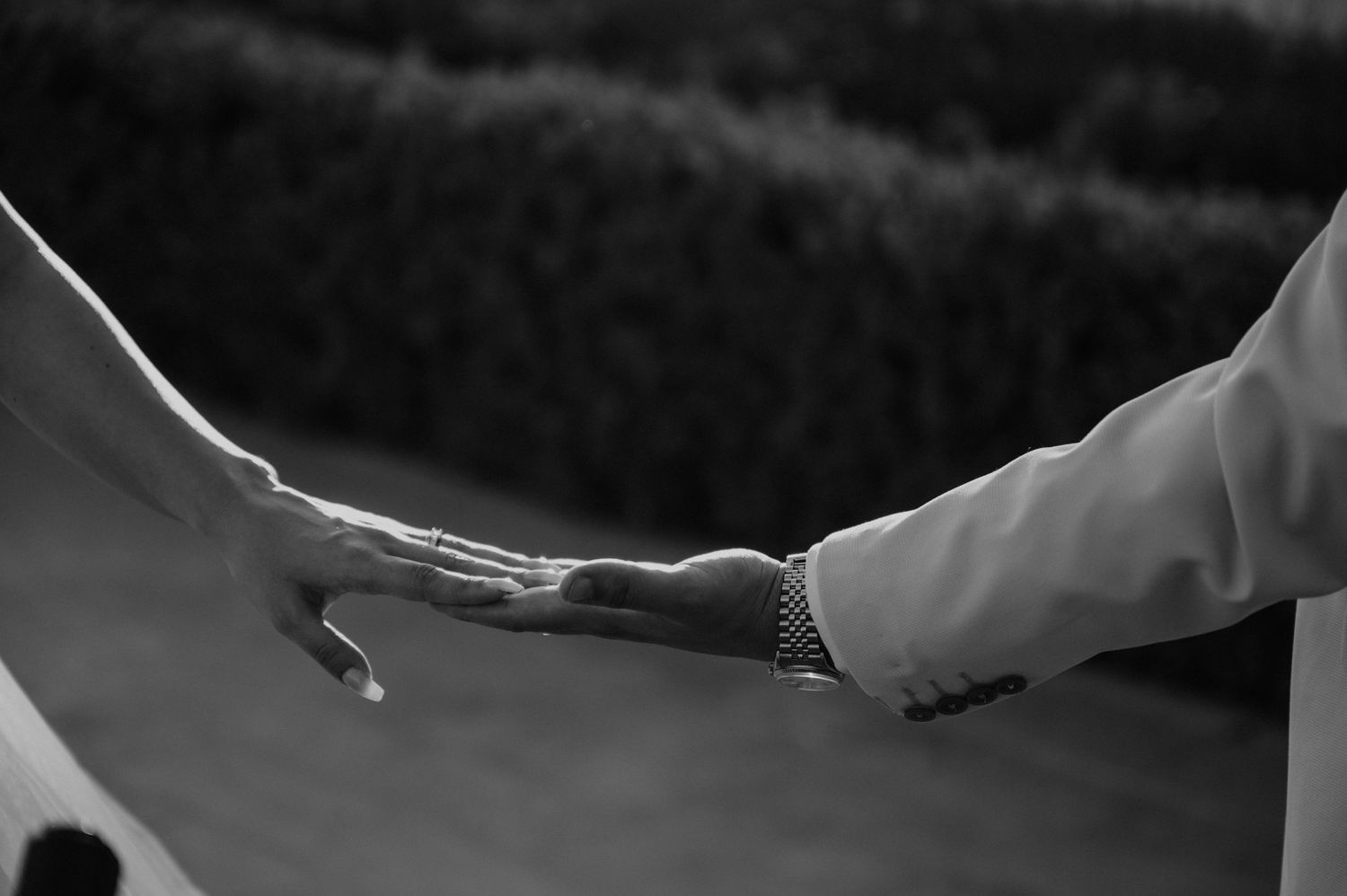 Black and white artistic shot of hands reaching toward each other.
