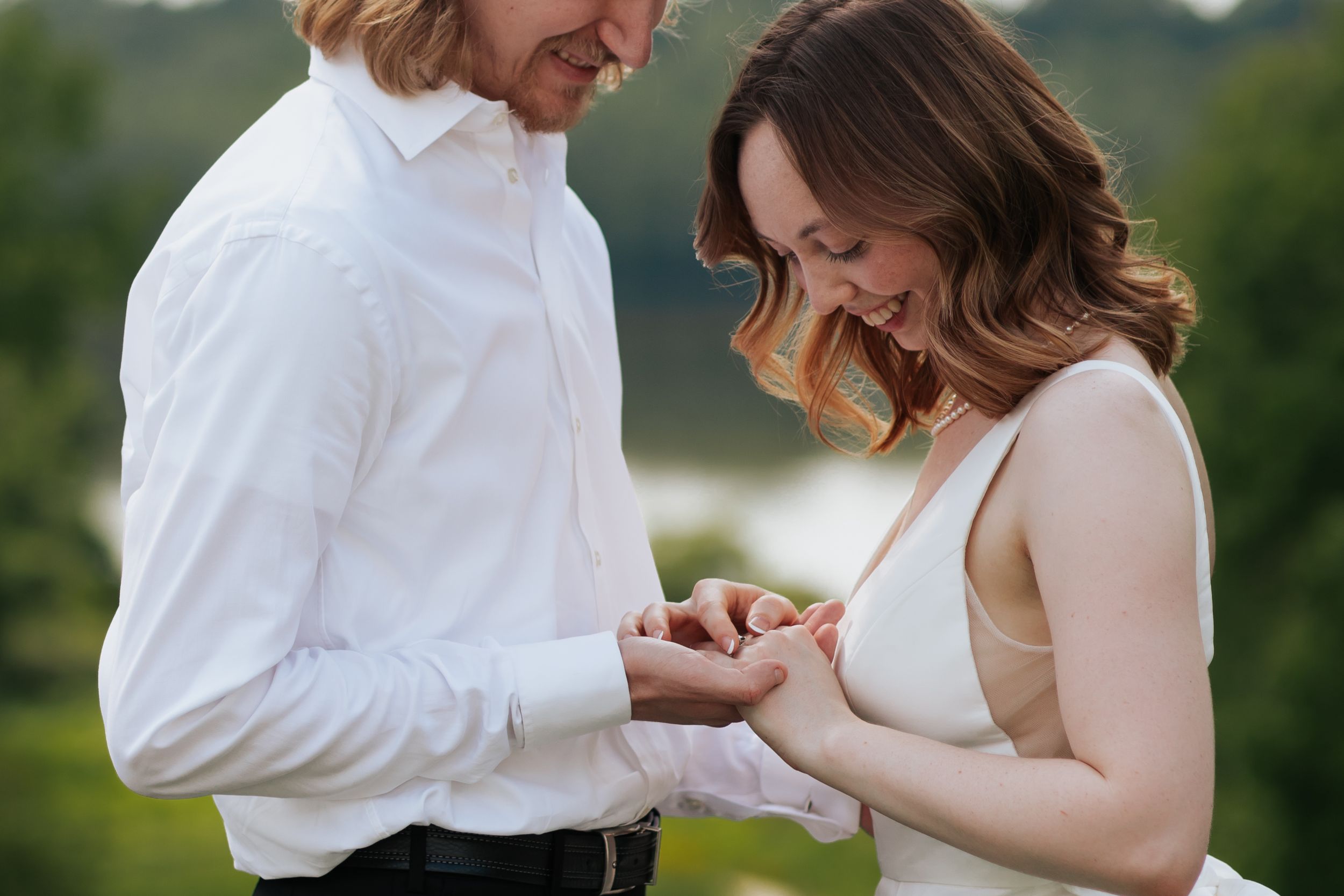 A couple shares an intimate moment outdoors while looking at a ring during a romantic proposal.