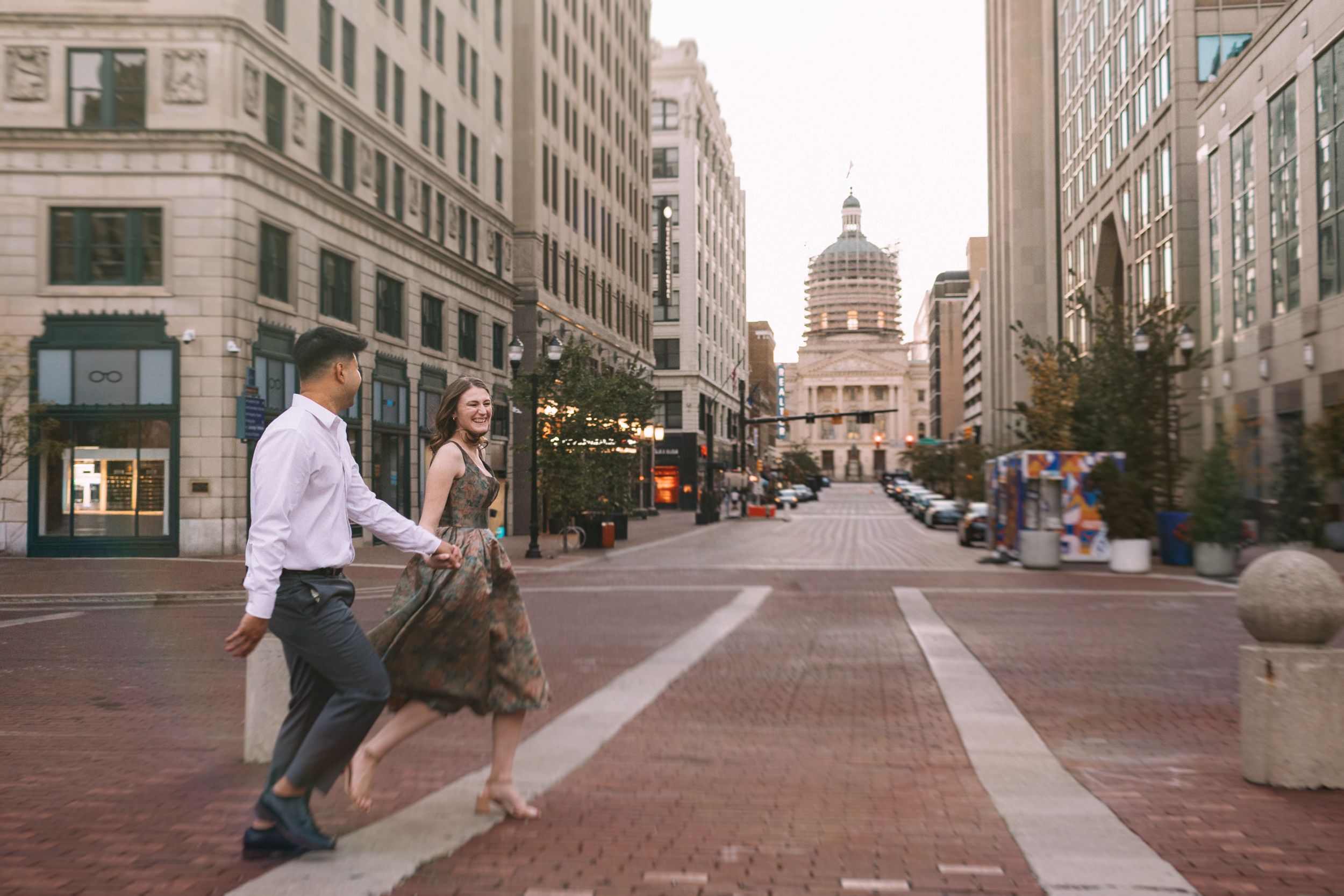 Couple walking along historic Market Street in downtown Indianapolis with the Indiana State Capitol dome in view.