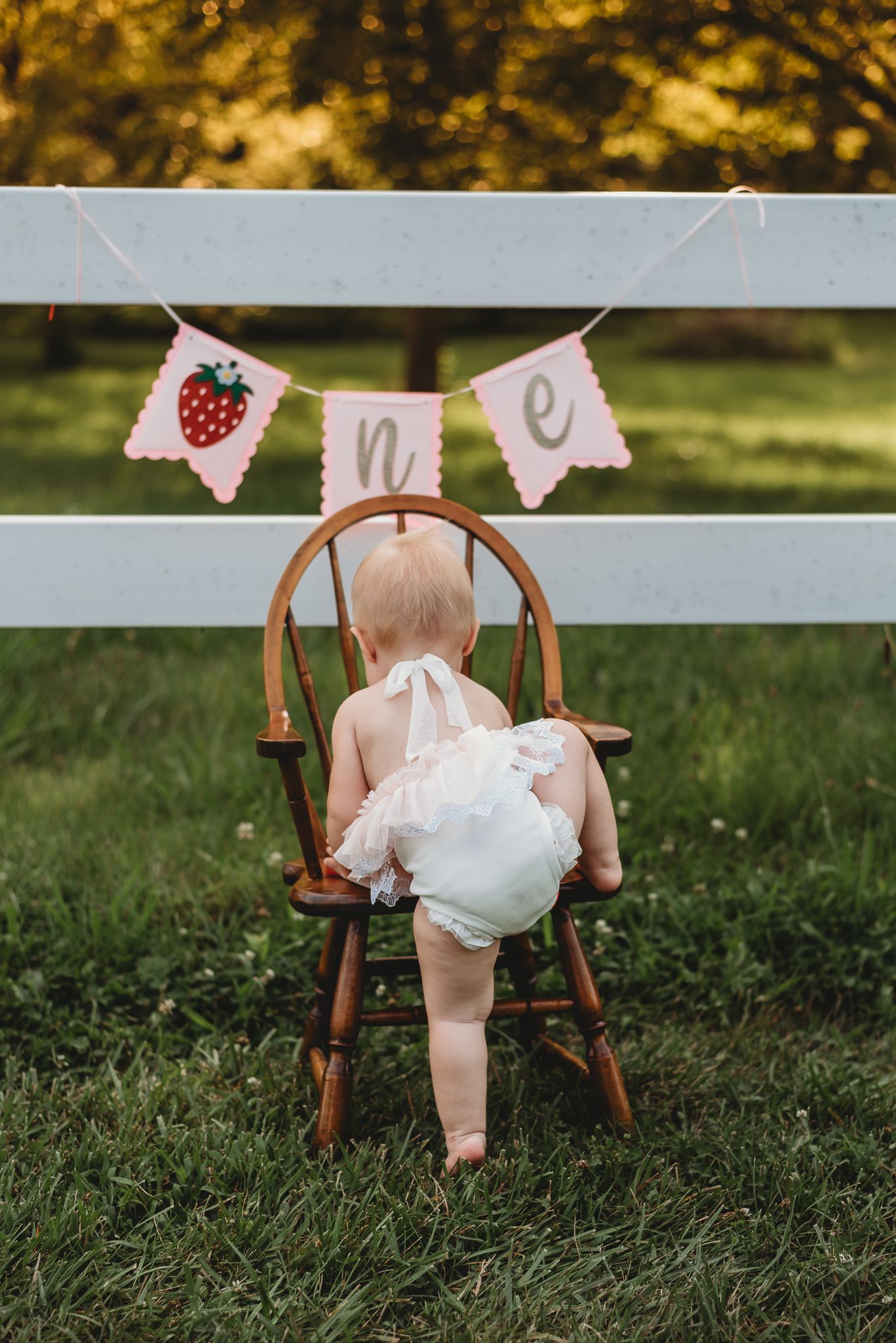 toddler climbing into a chair, under a "ONE" banner.