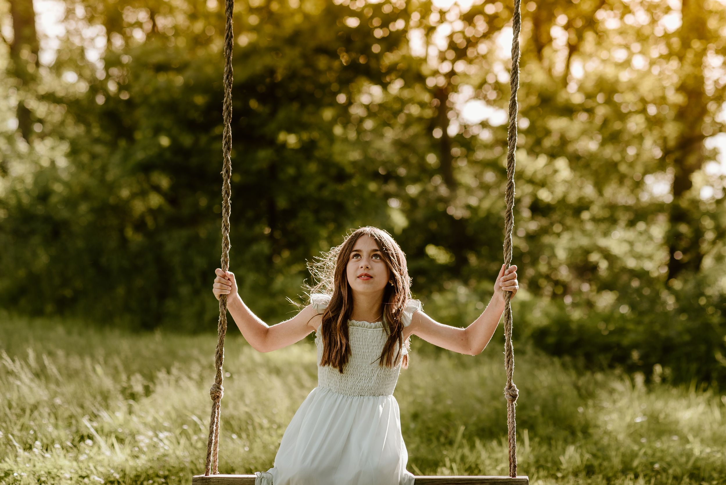 girl on a wooden swing looking up