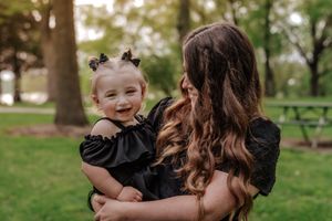 toddler smiles while mom looks at her
