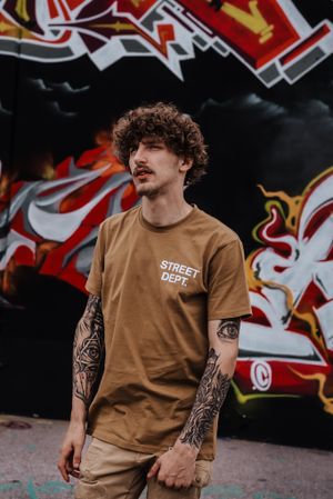 tattooed young man in front of graffiti