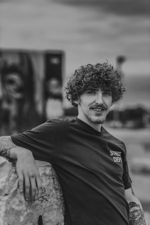 tattooed young man in front of graffiti