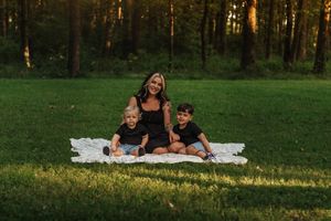 Mom posing with 2 boys on a white blanket