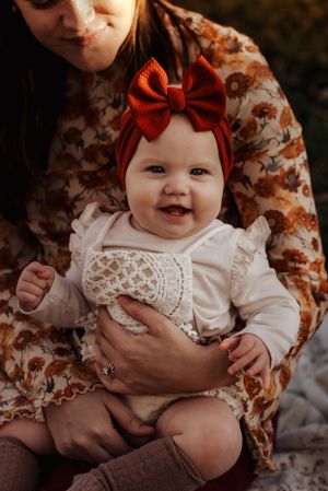 6 month old girl in her moms lap, big red bow