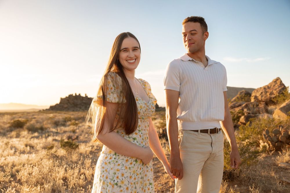 Couple walking hand in hand through desert landscape during golden hour at Joshua Tree National Park.