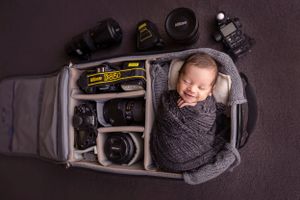 bebe recien nacido sonrie dentro de un bulto de camara nikon detres photography
