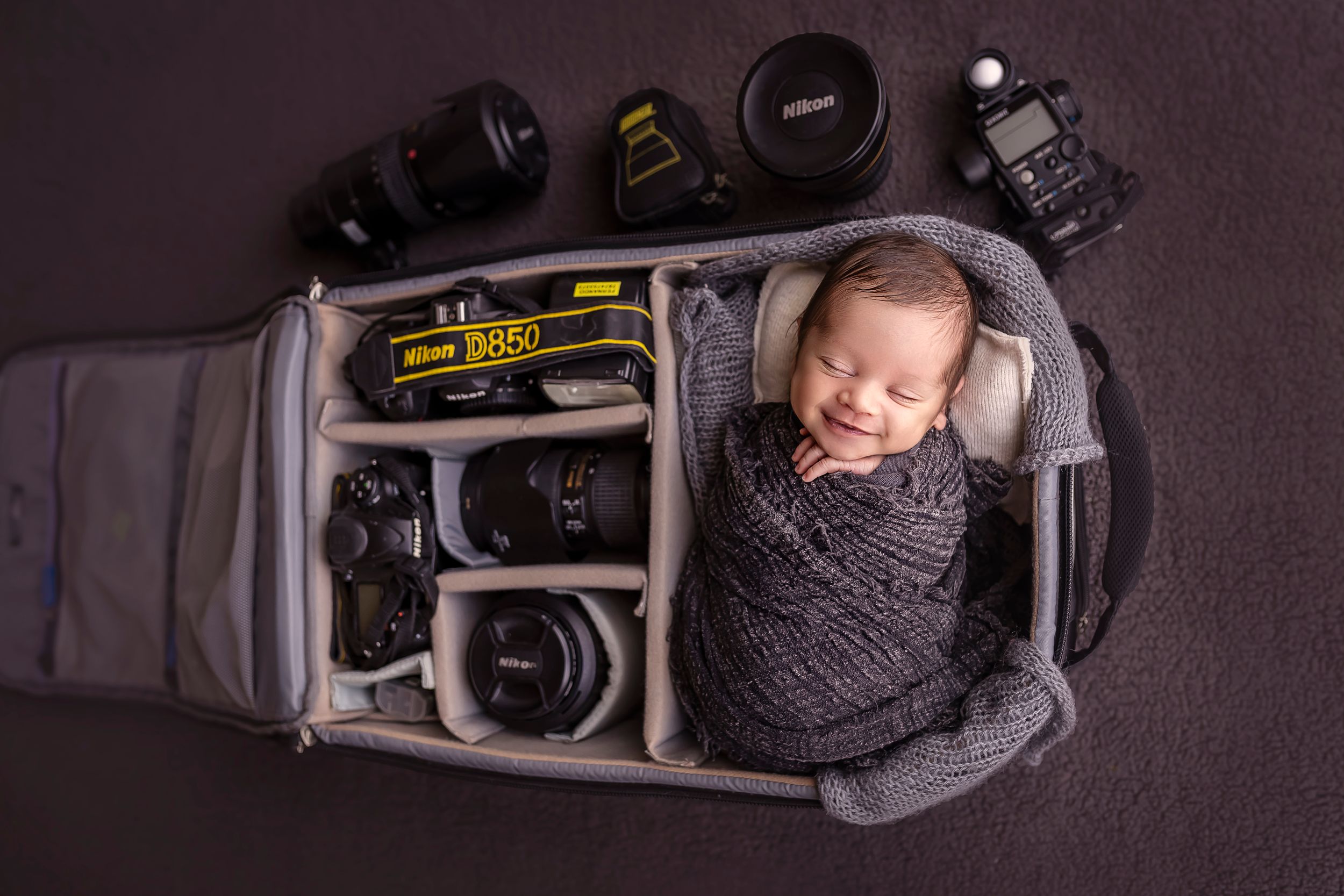 bebe recien nacido sonrie dentro de un bulto de camara nikon detres photography