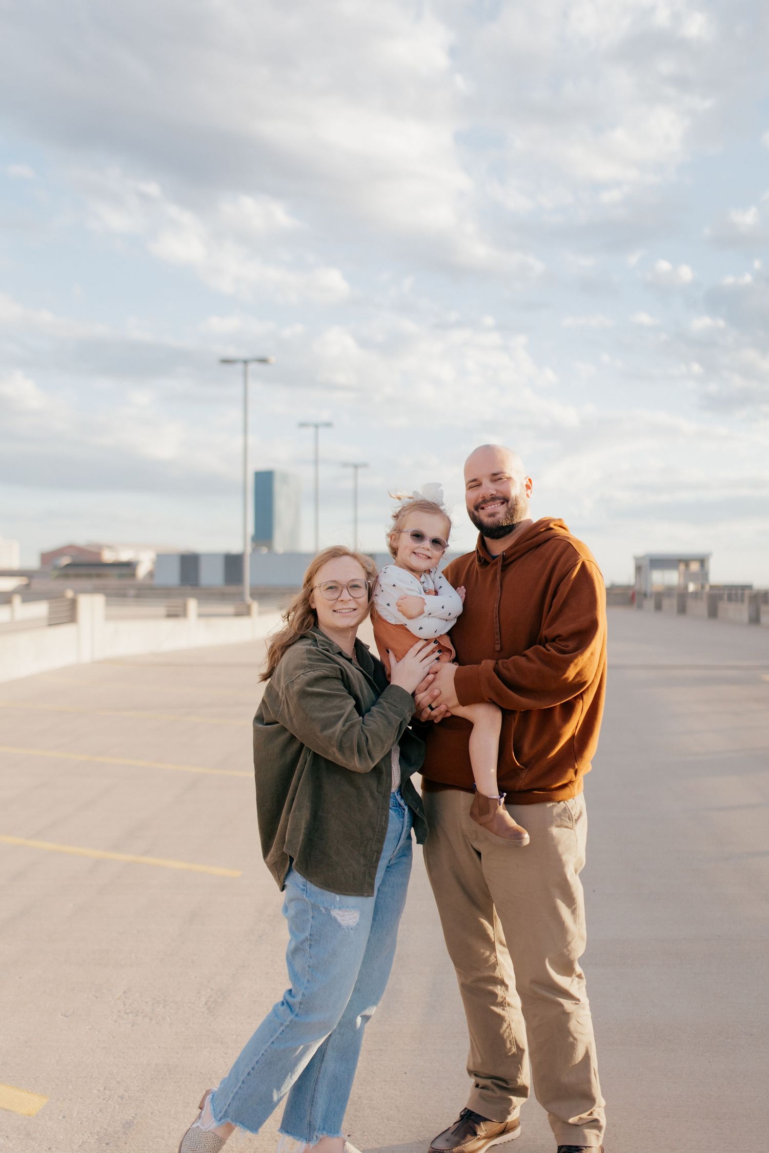 Three candid photos of a couple playfully interacting in an empty parking lot on an overcast day.