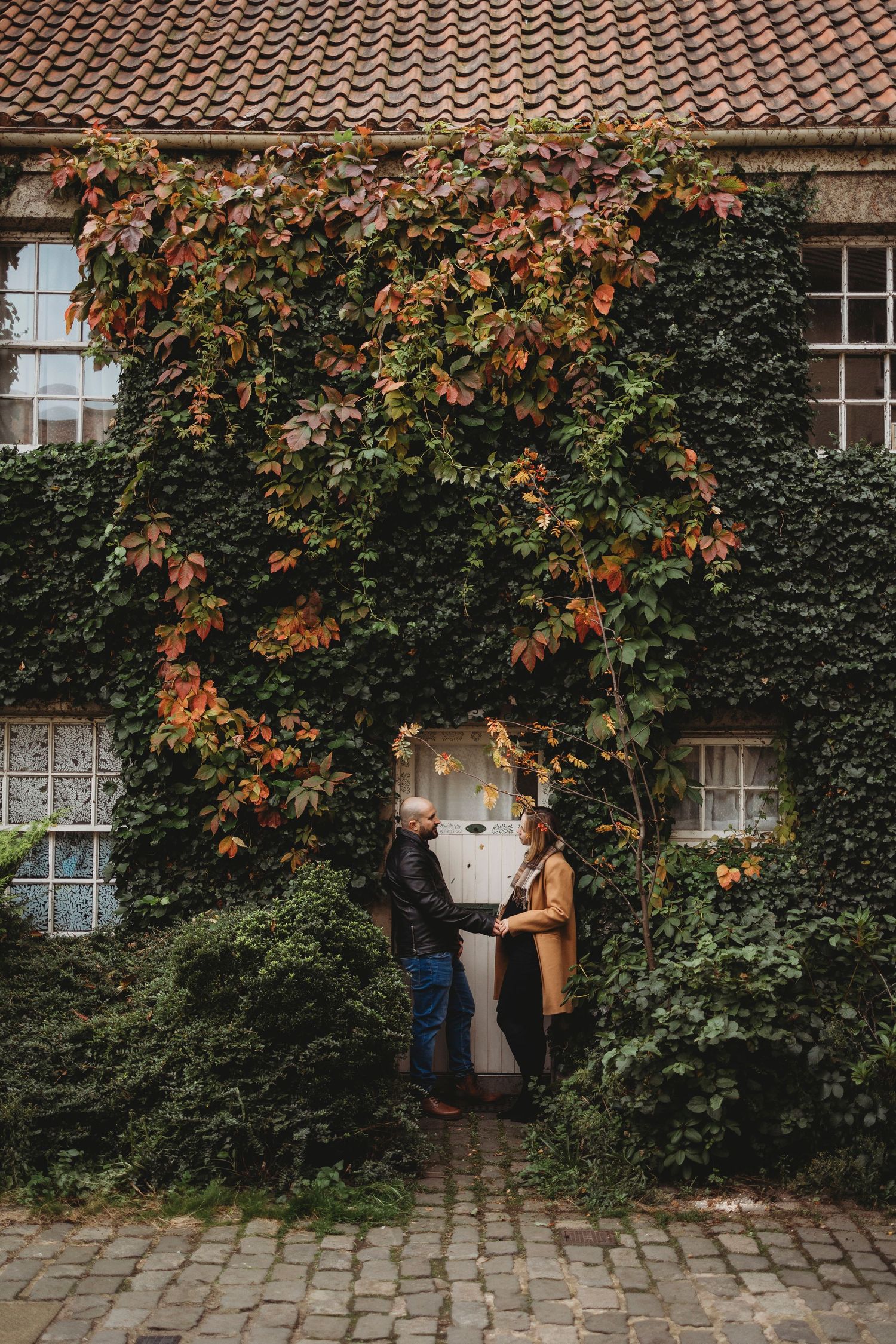 A couple sitting on stone steps during autumn with golden foliage in the background.