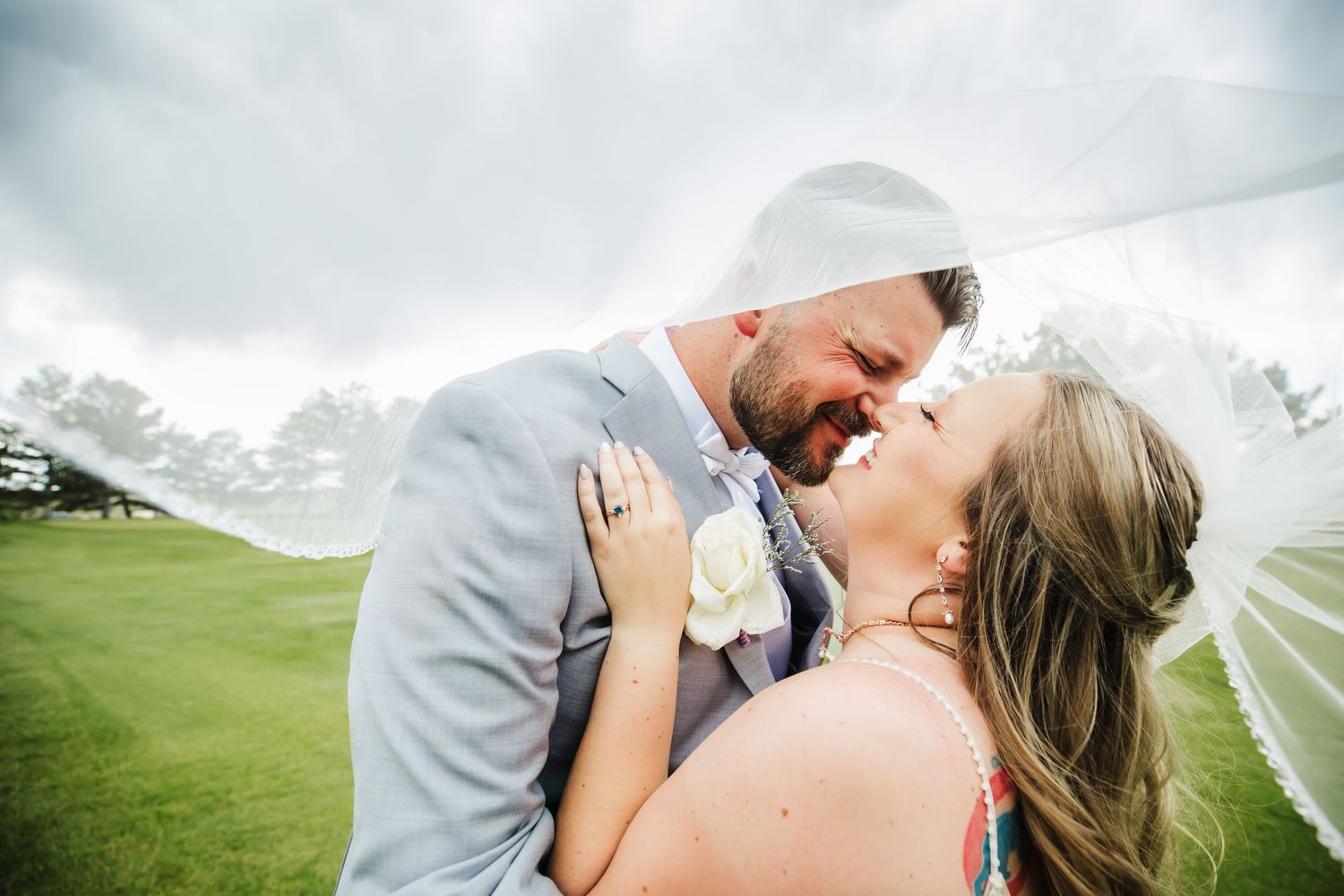 Bride and groom kissing in creek bed after wedding with blue sky and trees in Dickson, TN