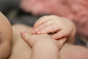 Close up view of a tiny baby hand gently grasping an adult finger in soft natural light.