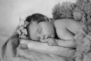 Peaceful newborn baby sleeping in black and white photo with floral decorations.