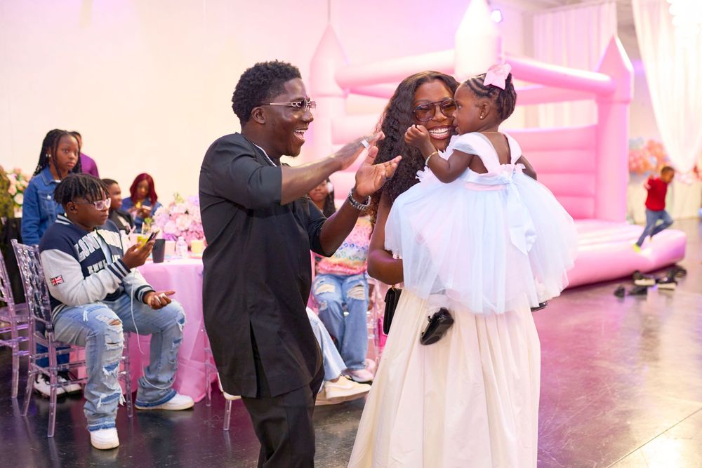 Guests dance and celebrate at a wedding reception with pink lighting and decor.