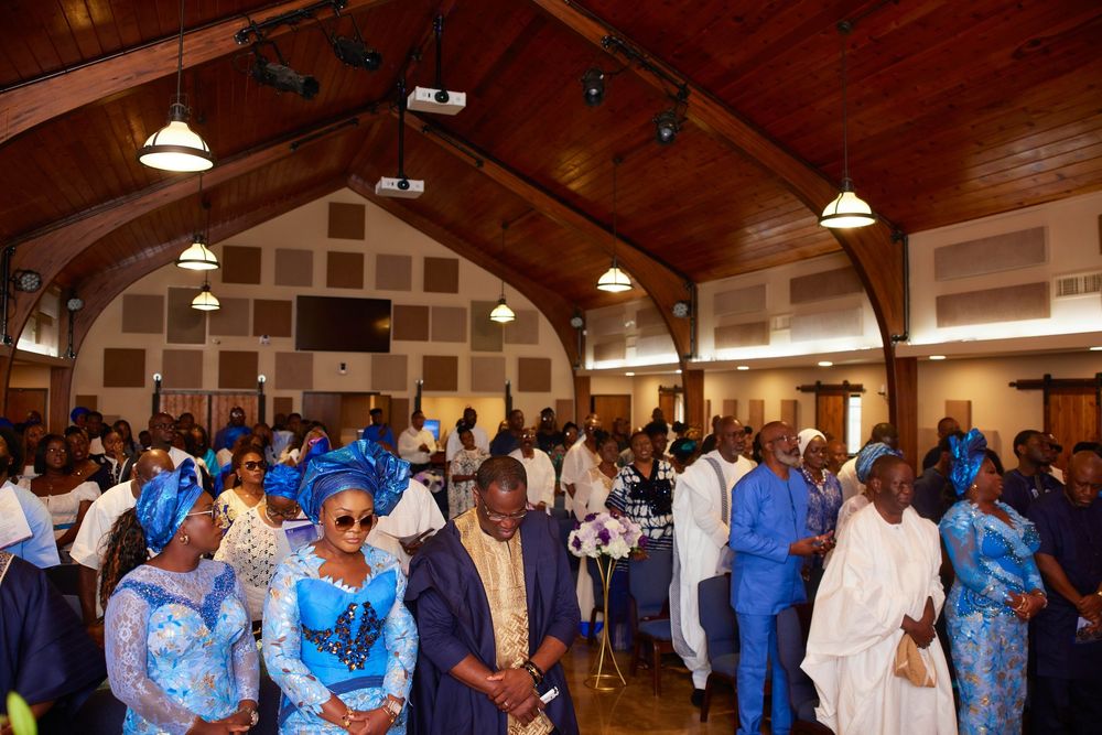 A large crowd gathers in a church hall wearing coordinated blue and white attire for a special event.