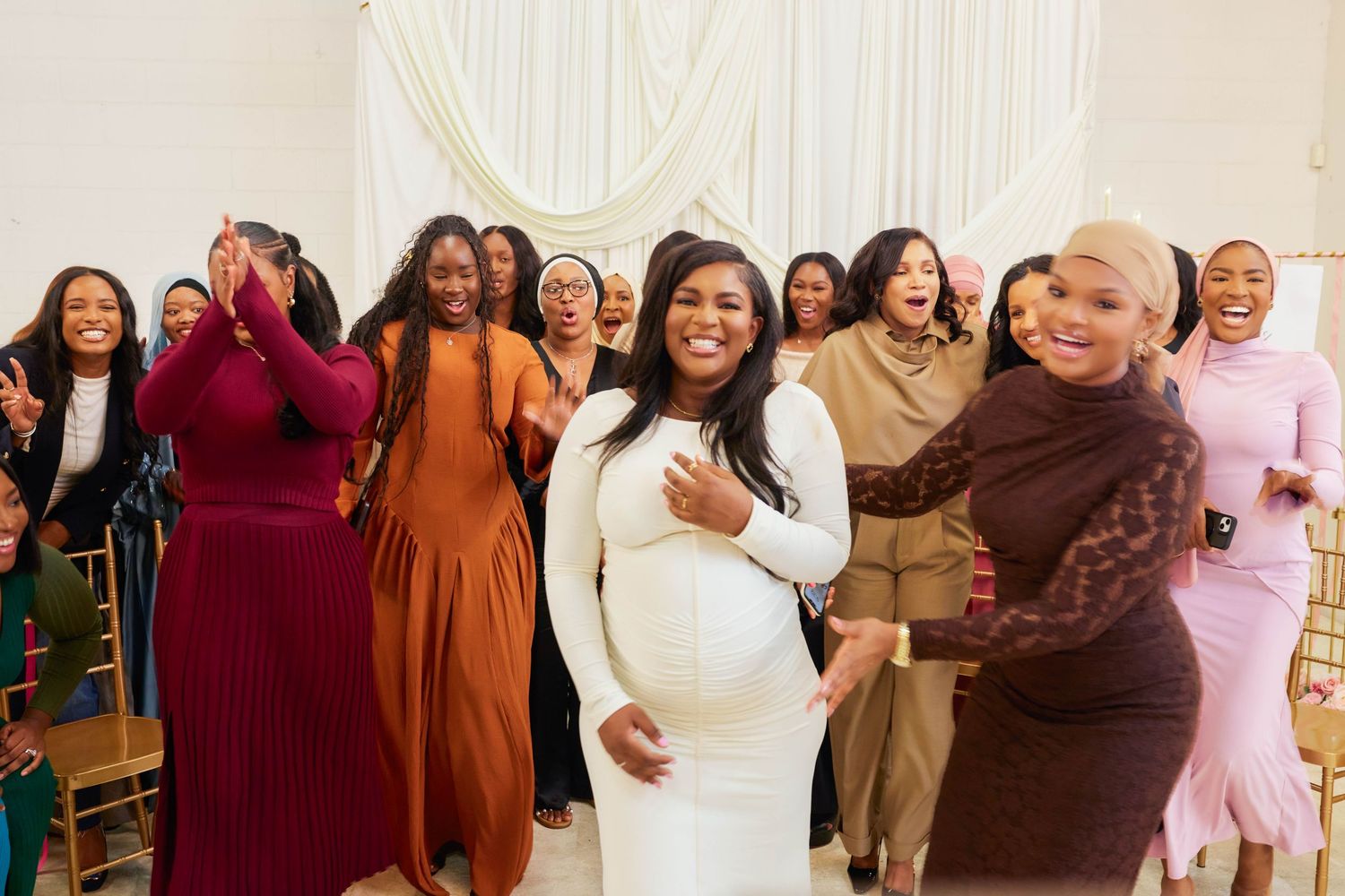 A group of people in formal attire pose together at a celebratory event, smiling and laughing.