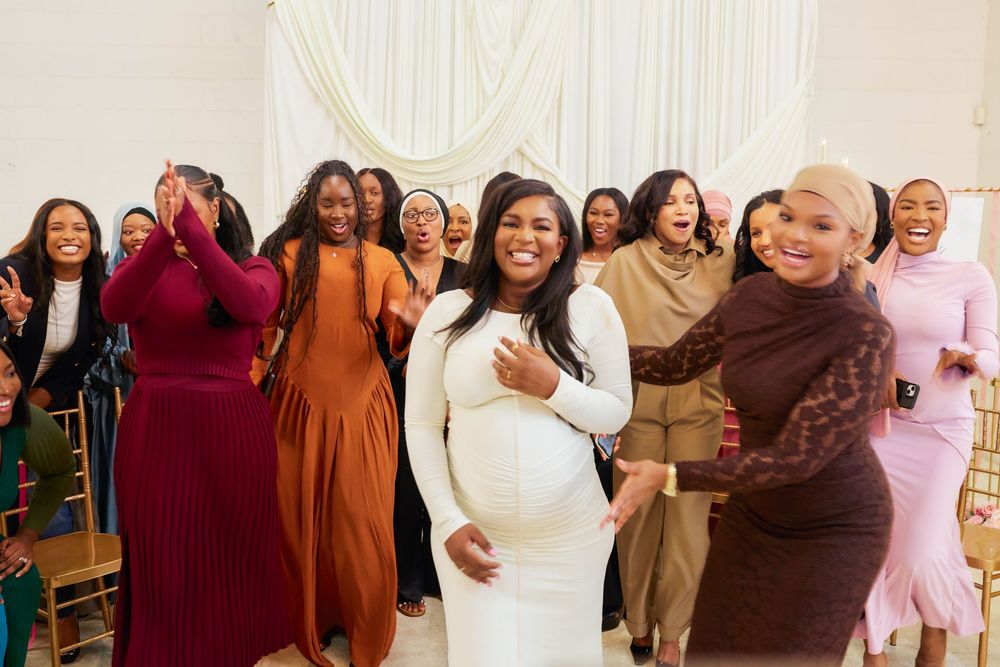A group of people in formal attire pose together at a celebratory event, smiling and laughing.