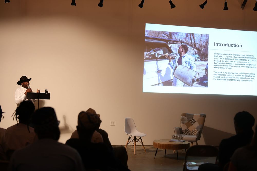 Silhouettes of people seated in a dark room watching a presentation on a projector screen.