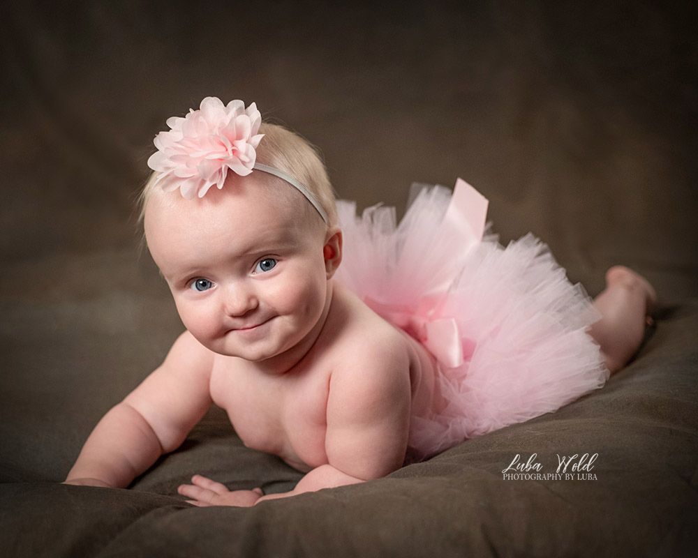 baby girl laying on her tummy wearing a pink headband and tutu skirt by newborn photographer Luba Wold in Post Falls Idaho