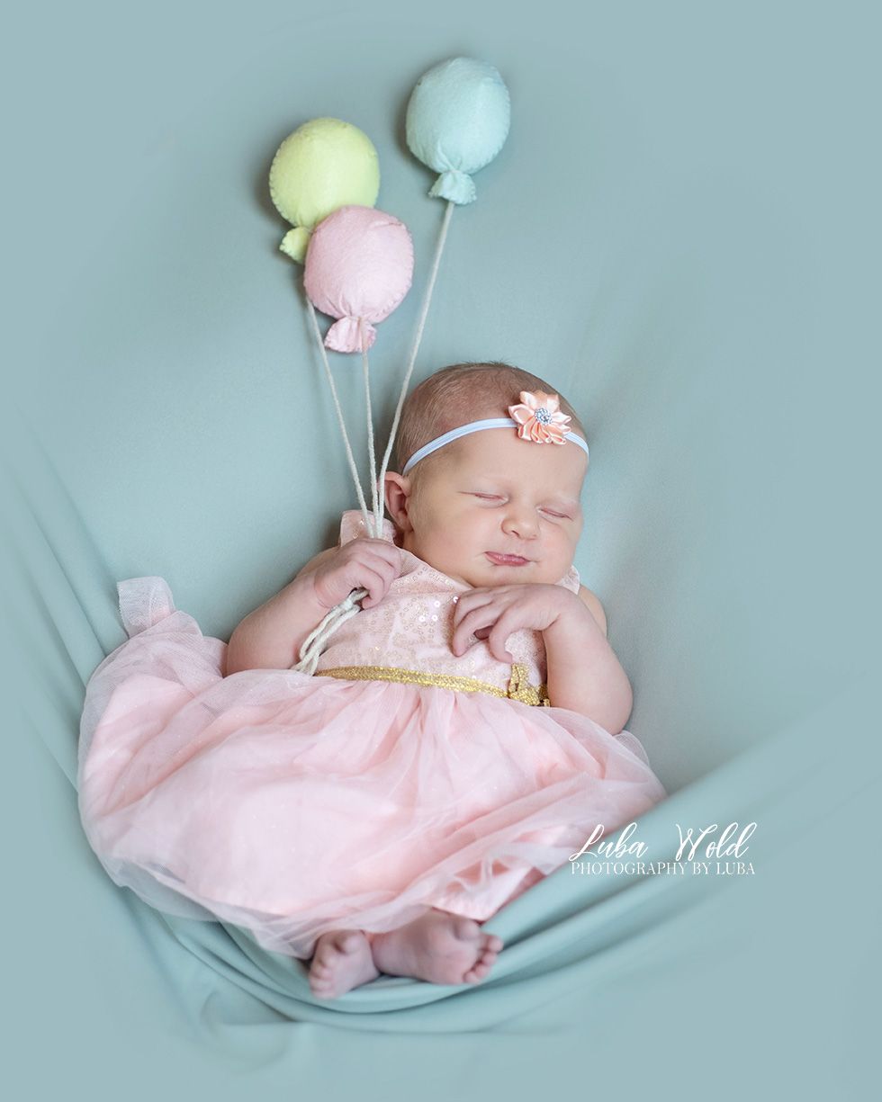 newborn baby girl with balloons wearing light pink dress by studio photographer in Post Falls Idaho Luba Wold