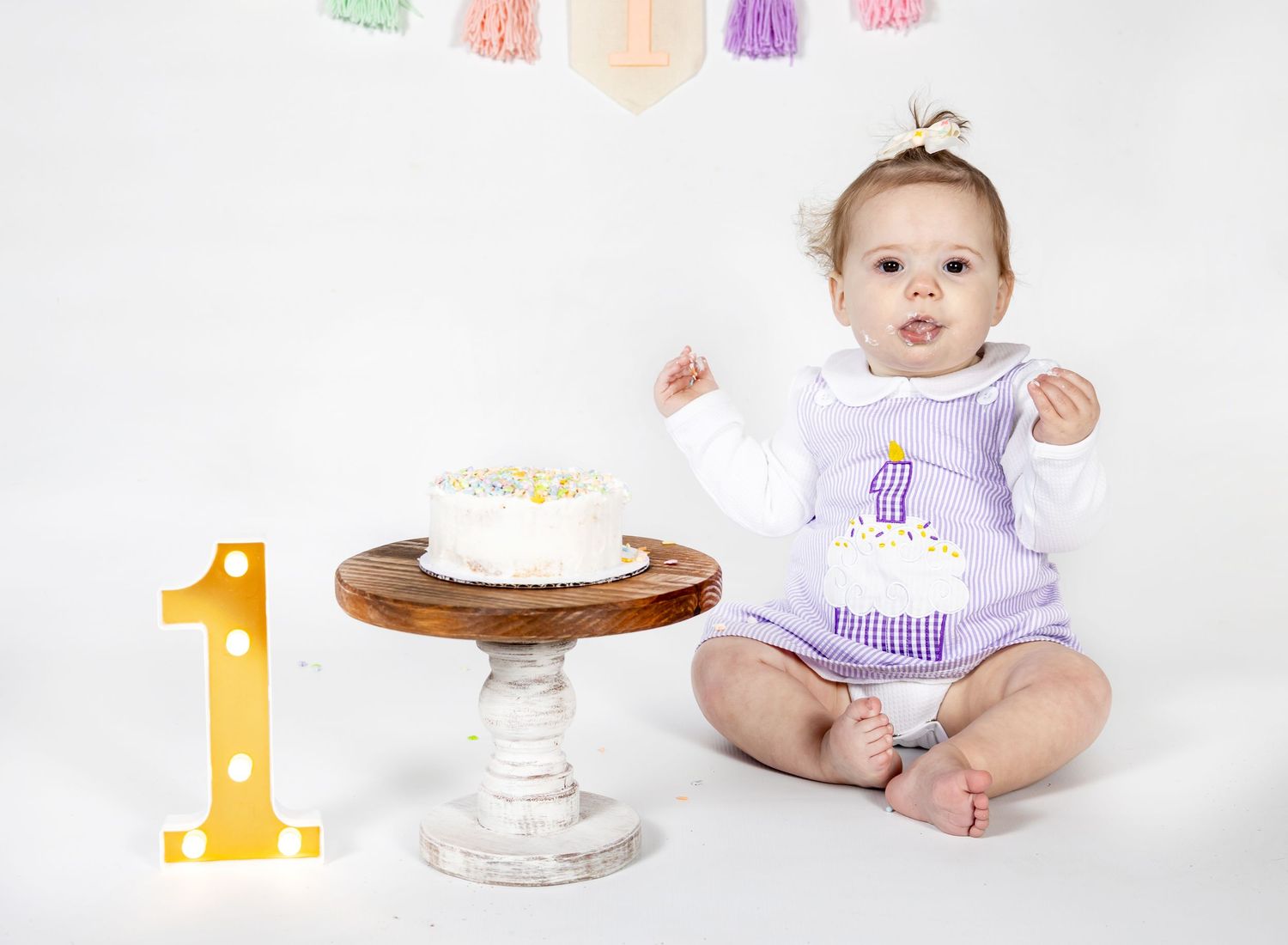cake smash photography images showing a first birthday celebration with colorful decorations.