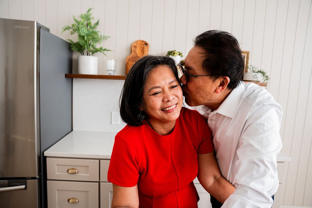 A couple in red and white outfits share tender moments together in a series of candid photos at home.