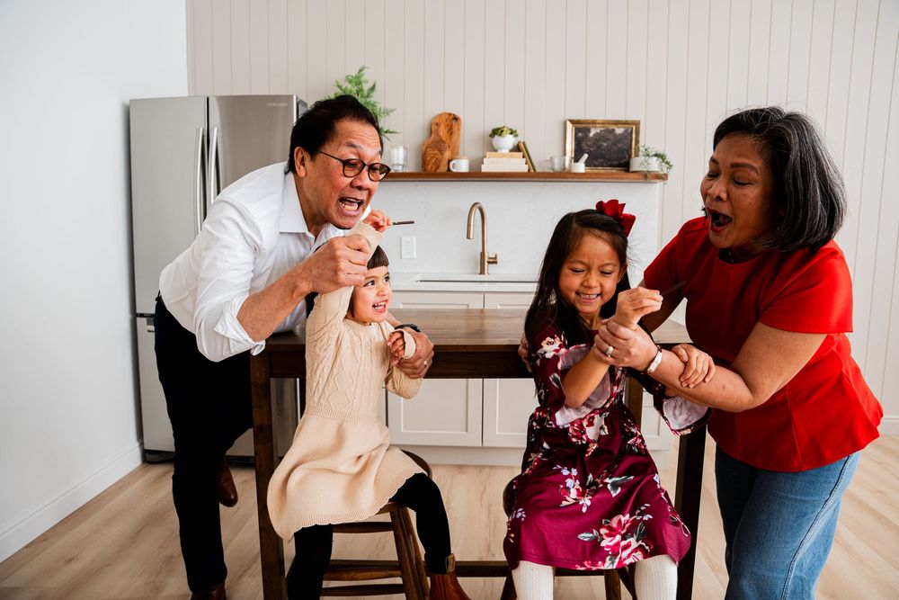 A group of people sharing joyful moments and laughter while gathered together in a kitchen setting.