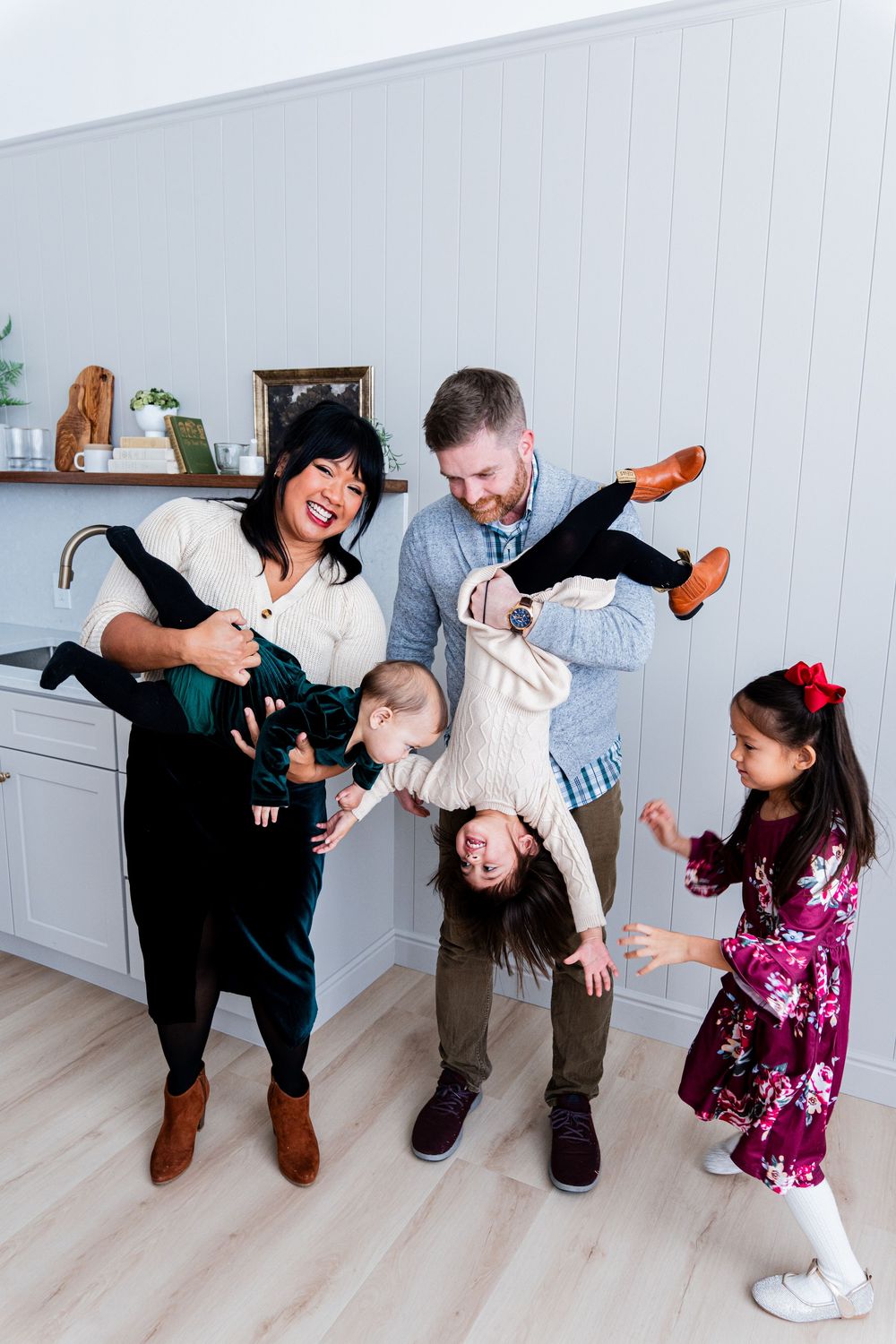 A playful family moment captured in a sequence showing energetic interactions in a white modern room.