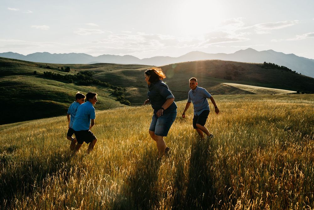 Group hiking through golden wheat fields at sunset with mountains in the background.