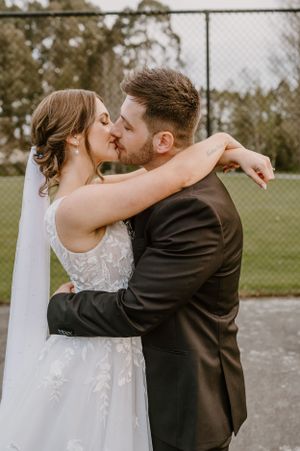 Romantic wedding moment captured as couple shares intimate kiss in outdoor setting.