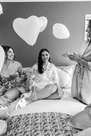 Black and white photo of a carefree morning celebration with heart shaped balloons and matching robes.