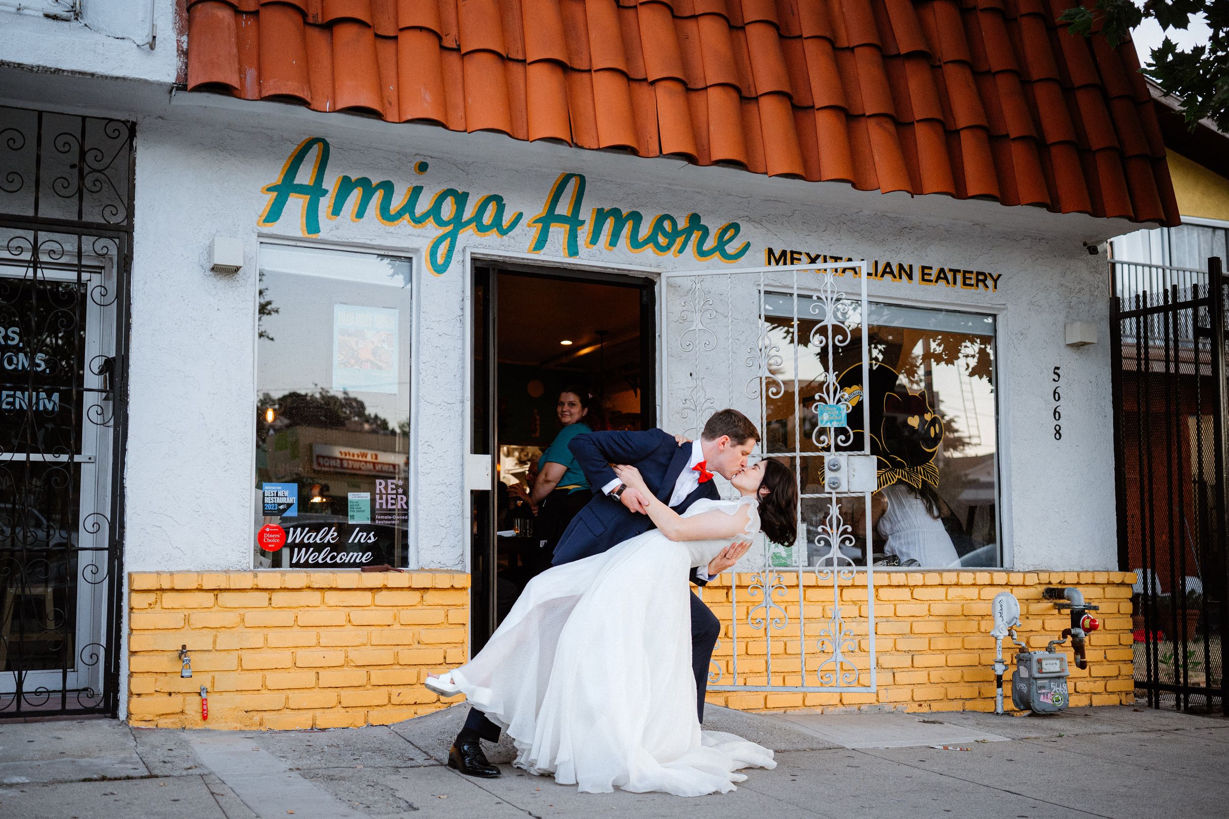 Bride and groom share a romantic dip kiss outside Amiga Amore Mexican Eatery on their wedding day.