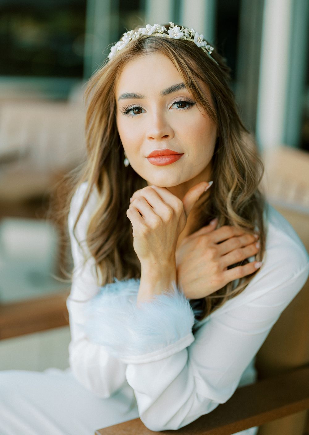 Portrait of someone in a white sweater with soft makeup and a delicate crown accessory.