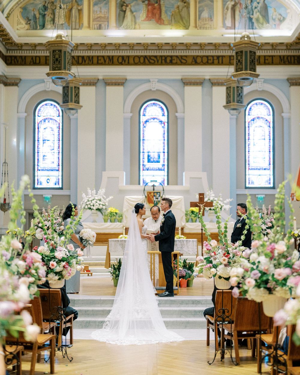 Elegant church wedding ceremony with floral arrangements and stained glass windows in a grand cathedral setting.