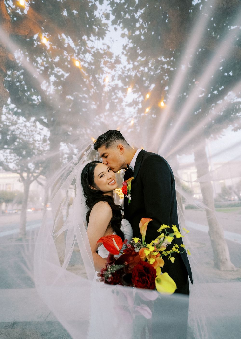 A romantic couple shares tender moments in a dreamy outdoor setting with sunbeams streaming through trees.