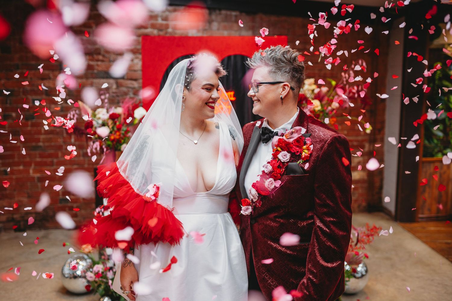 Wedding details with red and pink decor elements on rustic wooden surface.