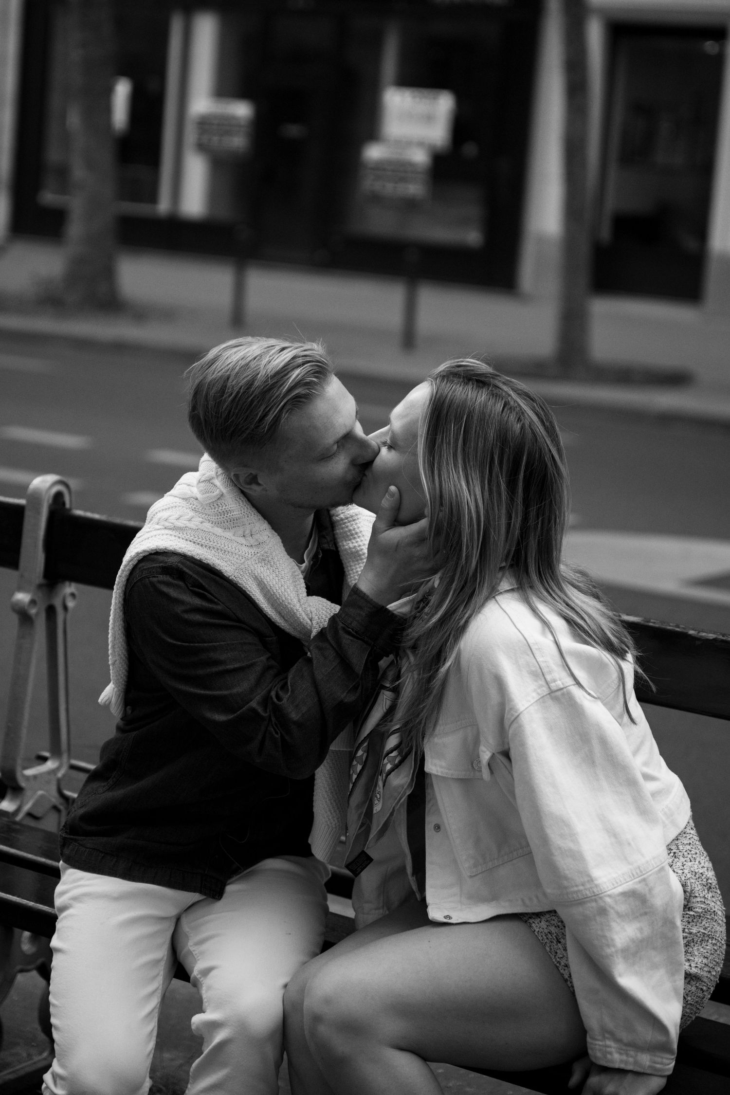 A couple enjoys wine on a Parisian balcony with the Eiffel Tower visible in the background.