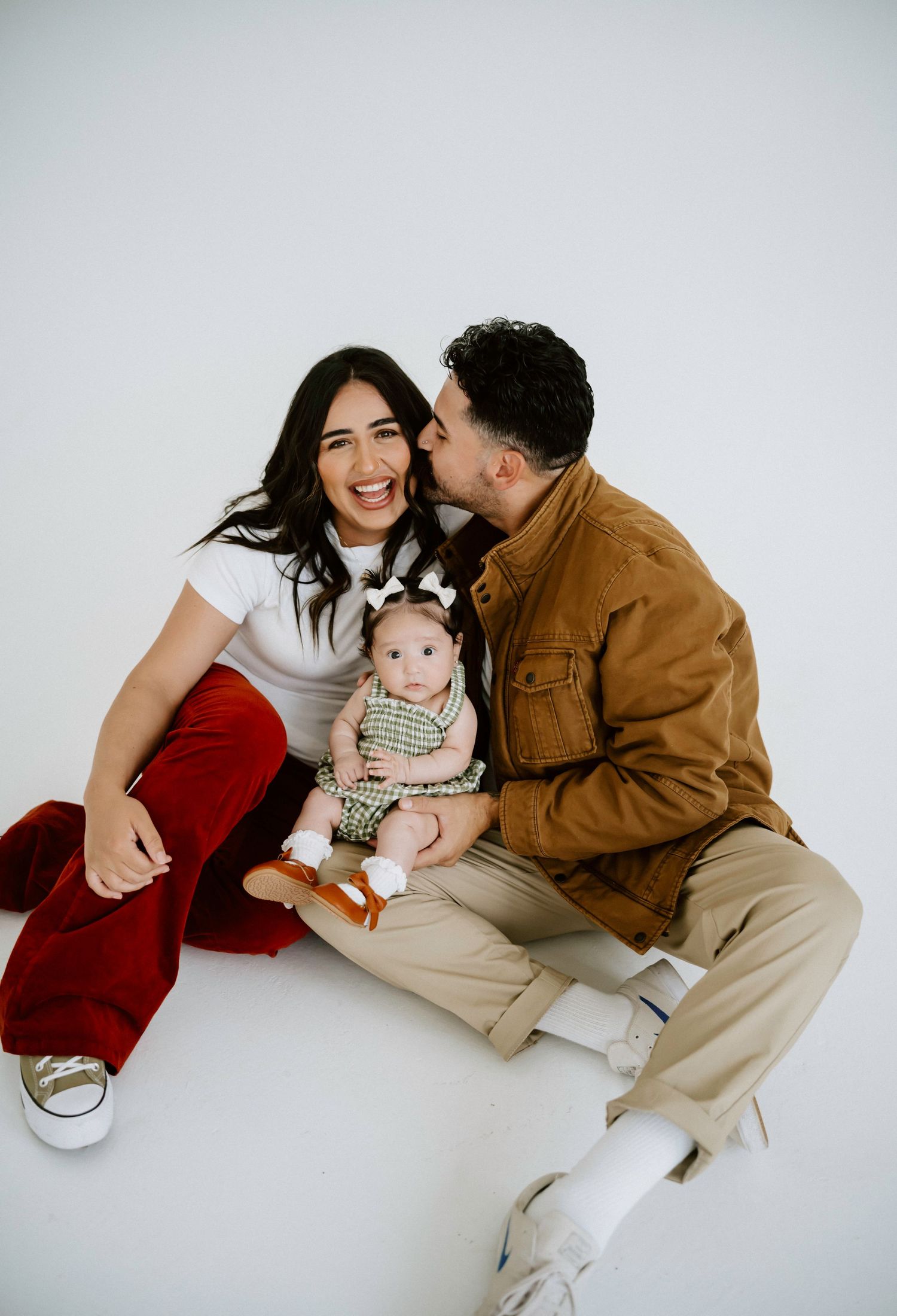 Studio family portrait session against white background in casual winter attire.