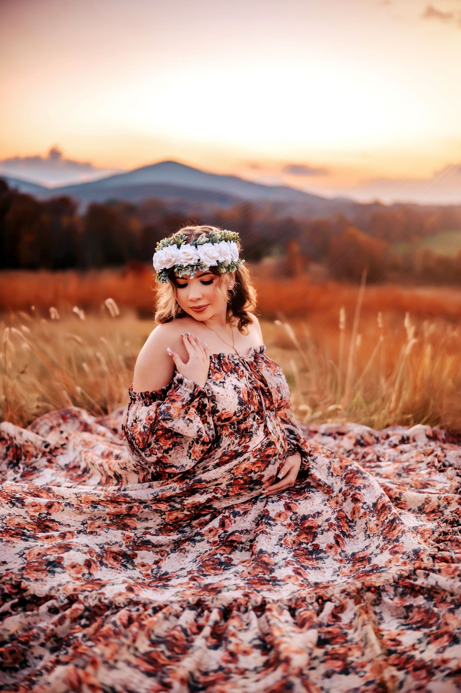Flowing pink dress spreads across grass in blooming spring orchard at sunset with peach blossoms in background.