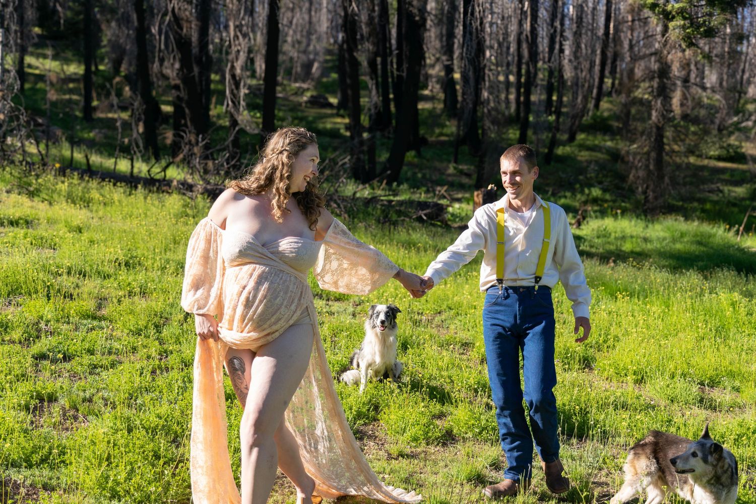 Couple walking hand in hand through sunny meadow with pets.